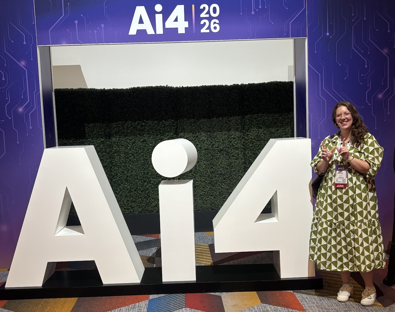 Sara smiling in front of the Ai4 sign at the conference.